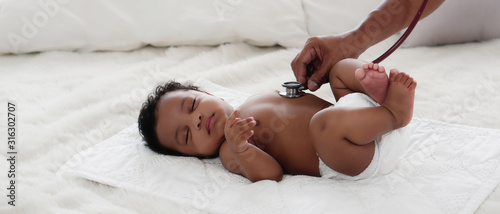 african american baby girl being health checkup with stethoscope photo