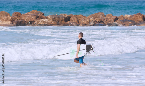 Surfer with a surfboard enters the water