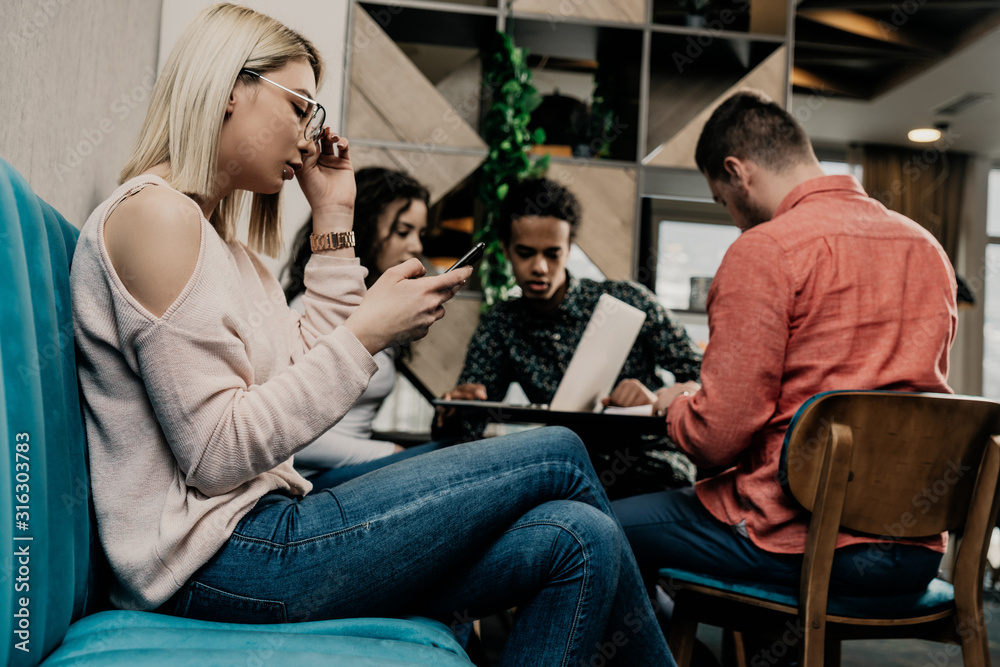 Diverse group of smiling young designer working together over a laptop during a meeting in the boardroom of a modern office Diverse group of smiling young designer working together over a laptop during a meeting in the boardroom of a modern office