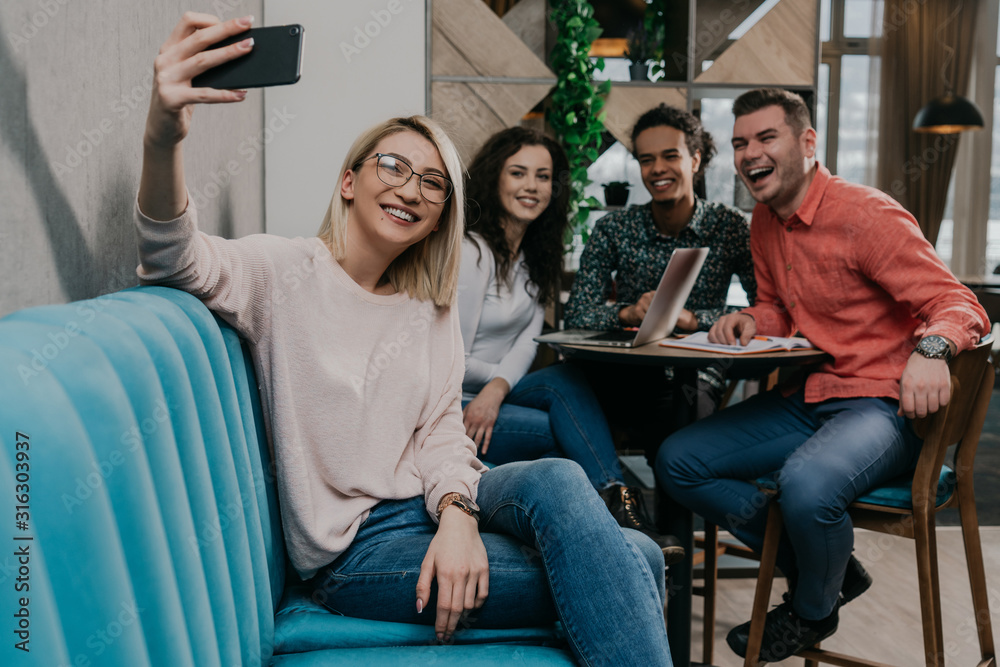 Diverse group of smiling young designer working together over a laptop during a meeting in the boardroom of a modern office Diverse group of smiling young designer working together over a laptop during a meeting in the boardroom of a modern office