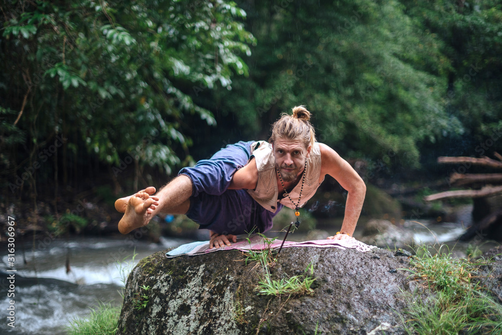 Yoga practice and meditation in nature. Man practicing near river Yoga practice and meditation in nature. Man practicing near river