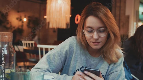 Portrait of young woman using phone in cafe and drinking coffe