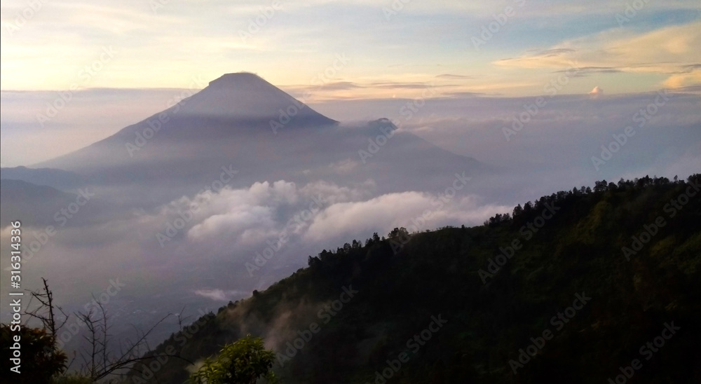 Foggy sunrise scenery of Mount Prau from Bukit Sikunir, Dieng Plateau.