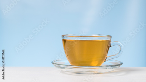 Tea in a glass Cup and saucer on a white table on a blue background.