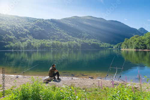 Fishing adventures, carp fishing. Man fishing on lake. Concept of patience, waiting, relaxation and healthy lifestyle in the nature 
