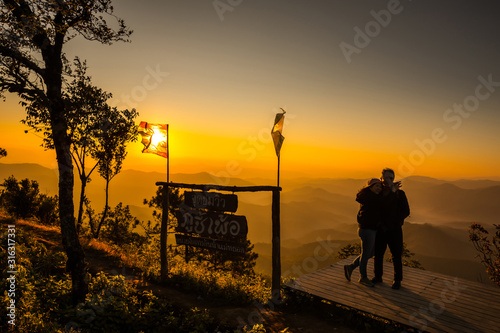 Romantic couple in love on mountain view misty morning at Phu chi phur viewpoint, Mae Hong Son Northern, Thailand. Thai language is name of viewpoint Phu chi phur. Relaxation and travel concept.