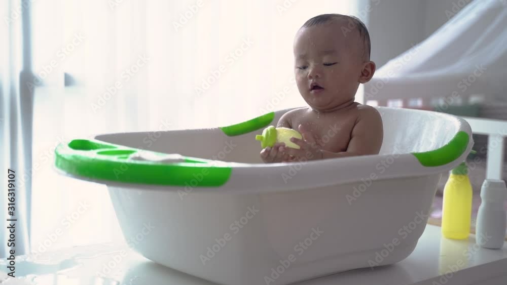 asian toddler taking a bath by himself in the basin asian toddler taking a bath by himself in the basin