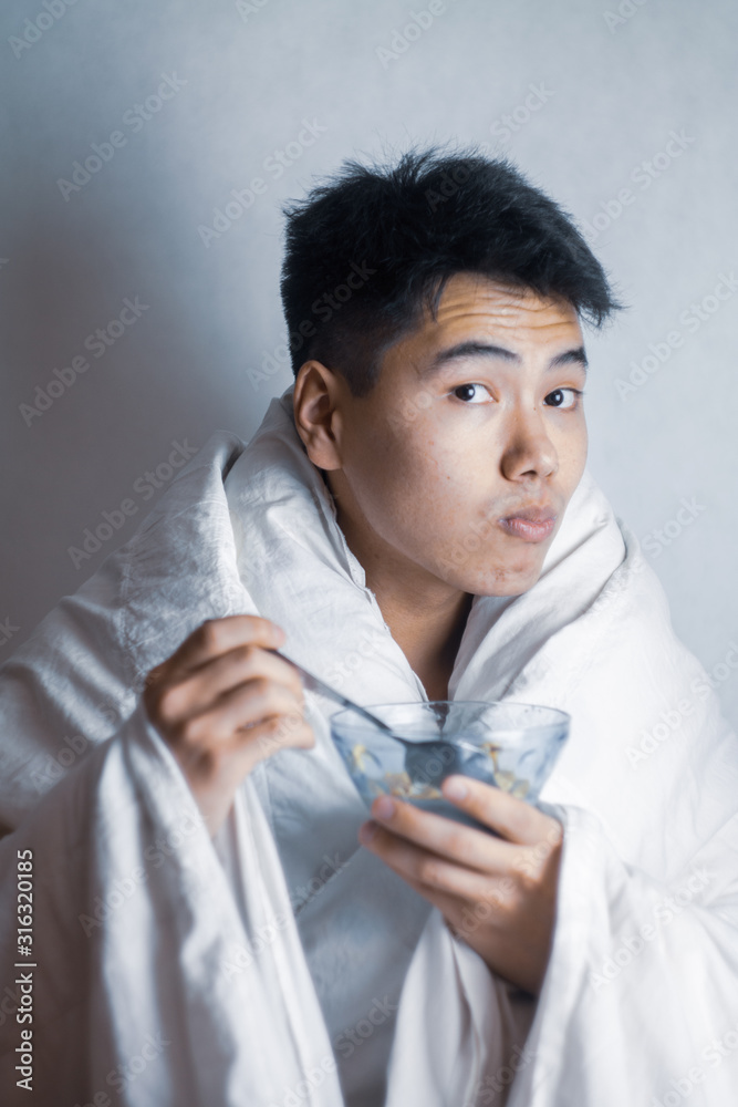 young man eating flakes wrapped in a blanket young man eating flakes wrapped in a blanket