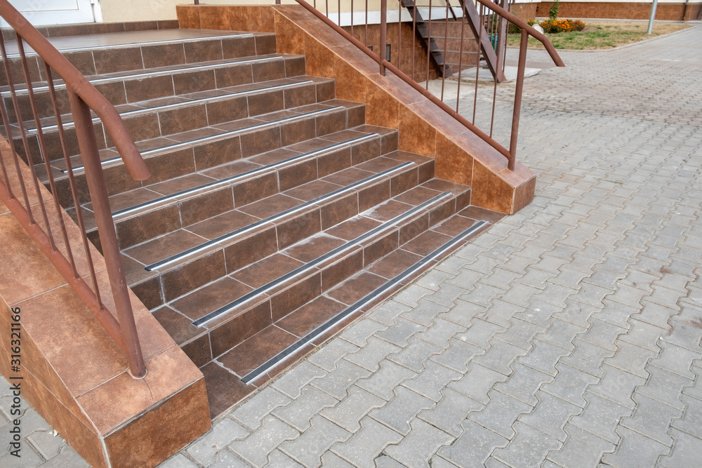 Concrete entrance stairs covered with ceramic tiles with metal railings ...