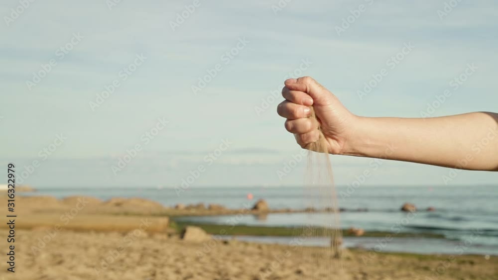 Gimbal shot slow motion of sand crumbling from woman hand on background of sea horizon, blue sky in sunny weather in summer time. Close up of woman holding a crumbling sand Gimbal shot slow motion of sand crumbling from woman hand on background of sea horizon, blue sky in sunny weather in summer time. Close up of woman holding a crumbling sand