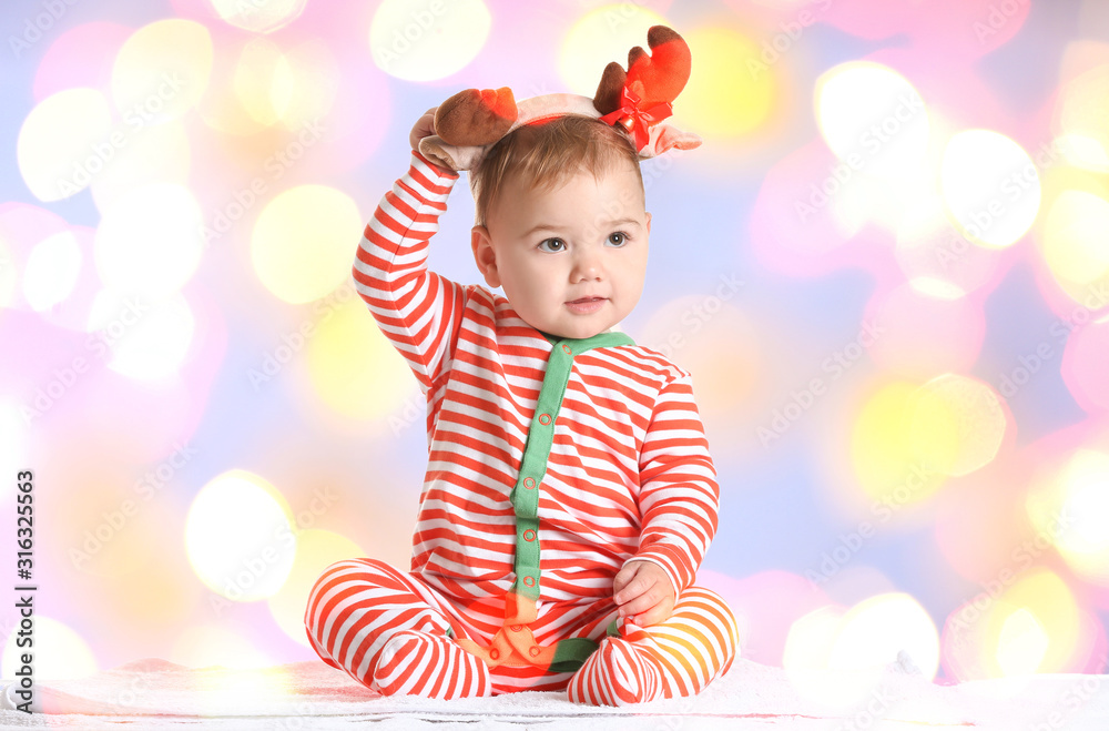 Cute little baby with Christmas decor against blurred Christmas lights