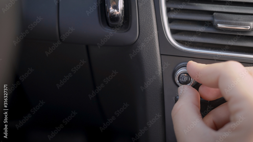human is adjusting volume of radio inside car, rotating handle on control panel, close-up of hand