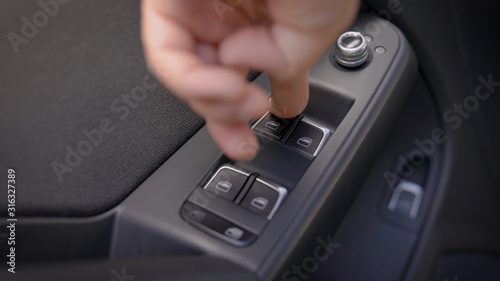driver is pressing buttons of window switches with remote control inside modern car, closeup view of hand © kustvideo