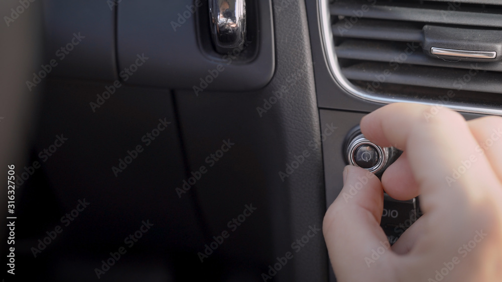 In the frame, a man s hand and a car audio volume knob. The driver or passenger adjusts the volume level of the music.
