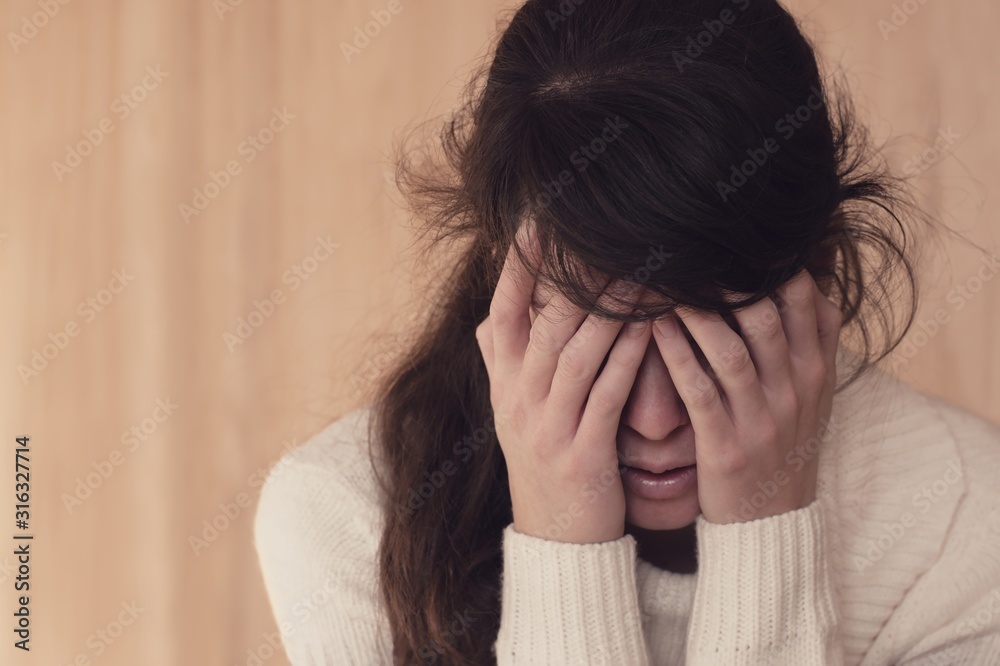 Emotional portrait of sad young woman holding her head in hands Emotional portrait of sad young woman holding her head in hands