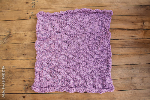 knitted linen of square shape of violet color on wooden boards