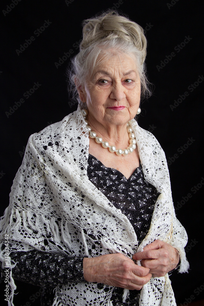 Portrait of a ninety year old woman. Beautiful old lady. Luxurious  grandmother on a black background. Elderly beauty. The gray-haired  well-groomed pensioner. Stock Photo