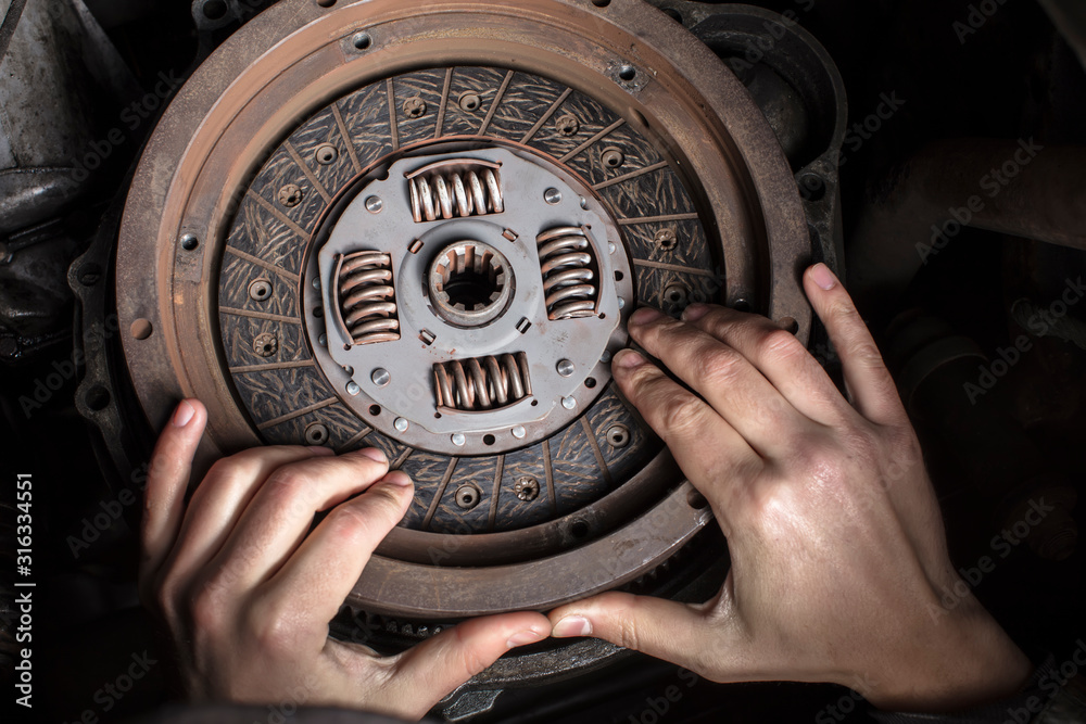 Car engine maintenance. Engine clutch repair. Hands with a mechanic with a clutch disc. Car engine maintenance. Engine clutch repair. Hands with a mechanic with a clutch disc.