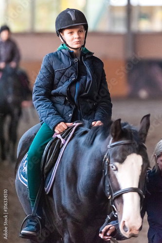 The boy rides a horse in the arena. © elena
