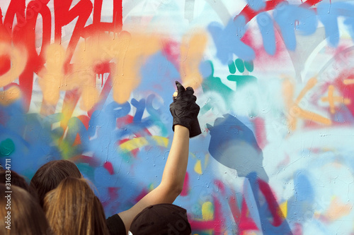 Fototapeta młodzi ludzie rysują graffiti na ścianie budynku