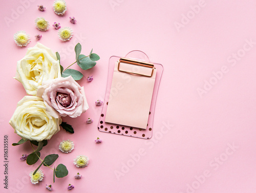 Clipboard and flowers on pink background