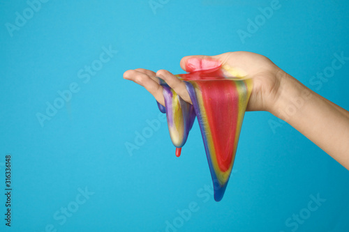 Fotografija Woman playing with colorful slime on light blue background, closeup