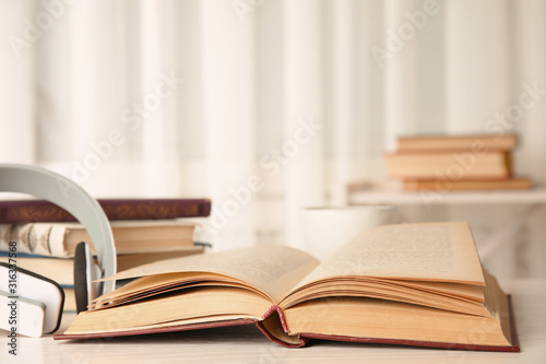 Open book and headphones on white wooden table