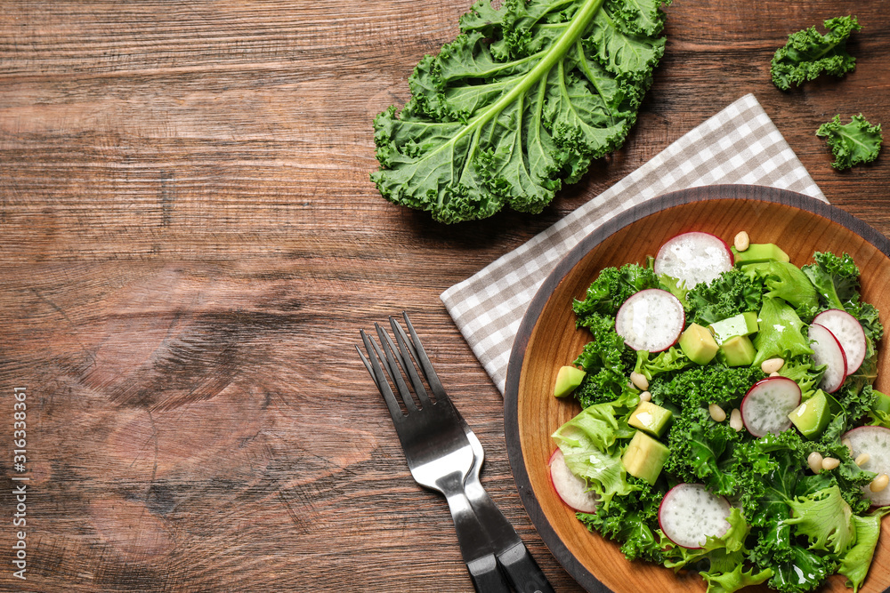 Delicious kale salad on wooden table, flat lay. Space for text Delicious kale salad on wooden table, flat lay. Space for text