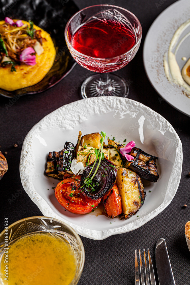 Modern Ukrainian cuisine in the European style. Grilled vegetables, tomato, red onion, eggplant, carrots and zucchini. Edible flowers as a decor. background image, copy space text Modern Ukrainian cuisine in the European style. Grilled vegetables, tomato, red onion, eggplant, carrots and zucchini. Edible flowers as a decor. background image, copy space text