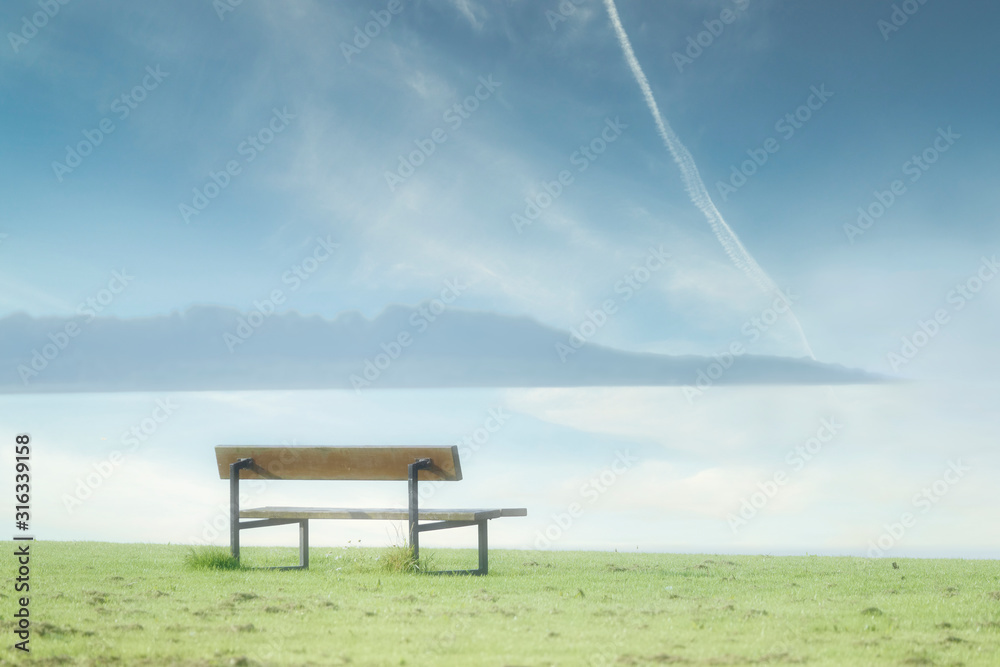 Lonely empty bench in open tranquil landscape by the sea for mindfulness and meditation Lonely empty bench in open tranquil landscape by the sea for mindfulness and meditation