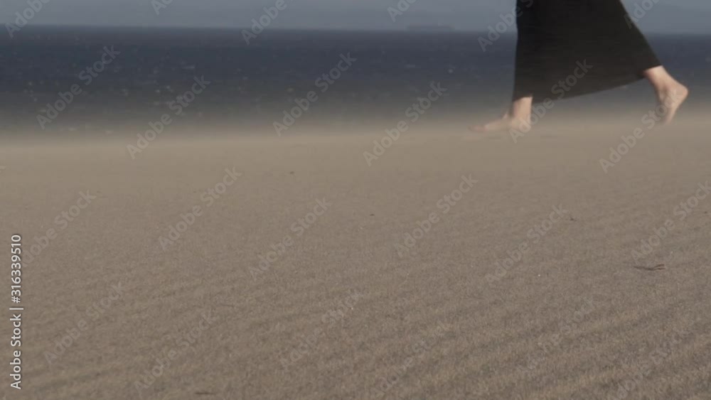 Pies de mujer caminando por la arena con viento HD