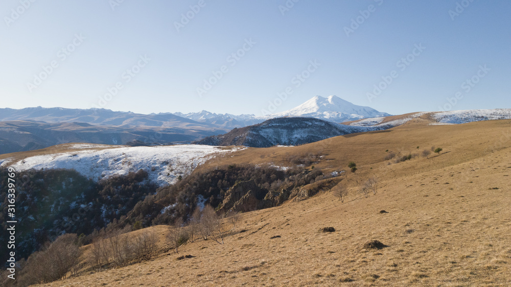 Spring landscape with views of a dry arid high-altitude field and mount Elbrus in the distance. Travel to Russia and the Caucasus