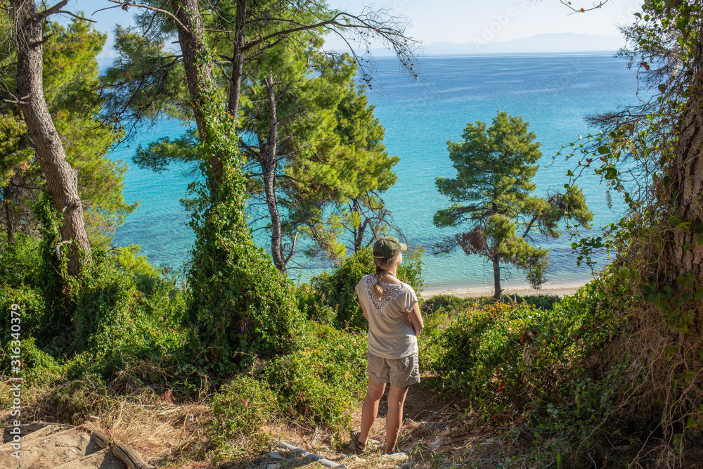 Tourist enjoying beautiful Greek landscapes during summer trip and vacations. Adult caucasian woman standing on top of hill looking at distance thoughtfully. Horizontal color photography. Tourist enjoying beautiful Greek landscapes during summer trip and vacations. Adult caucasian woman standing on top of hill looking at distance thoughtfully. Horizontal color photography.
