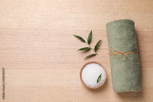 Flat lay composition with green towel on wooden table, space for text. Spa treatment