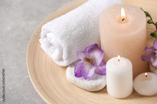 Beautiful composition with spa stones and burning candles on grey table, closeup