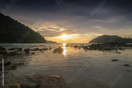 view seaside evening of many arch rocks in the sea with yellow sun light and cloudy sky background, sunset at Khao Chong Kad, Mu Ko Surin island, Phang Nga, southern of Thailand.