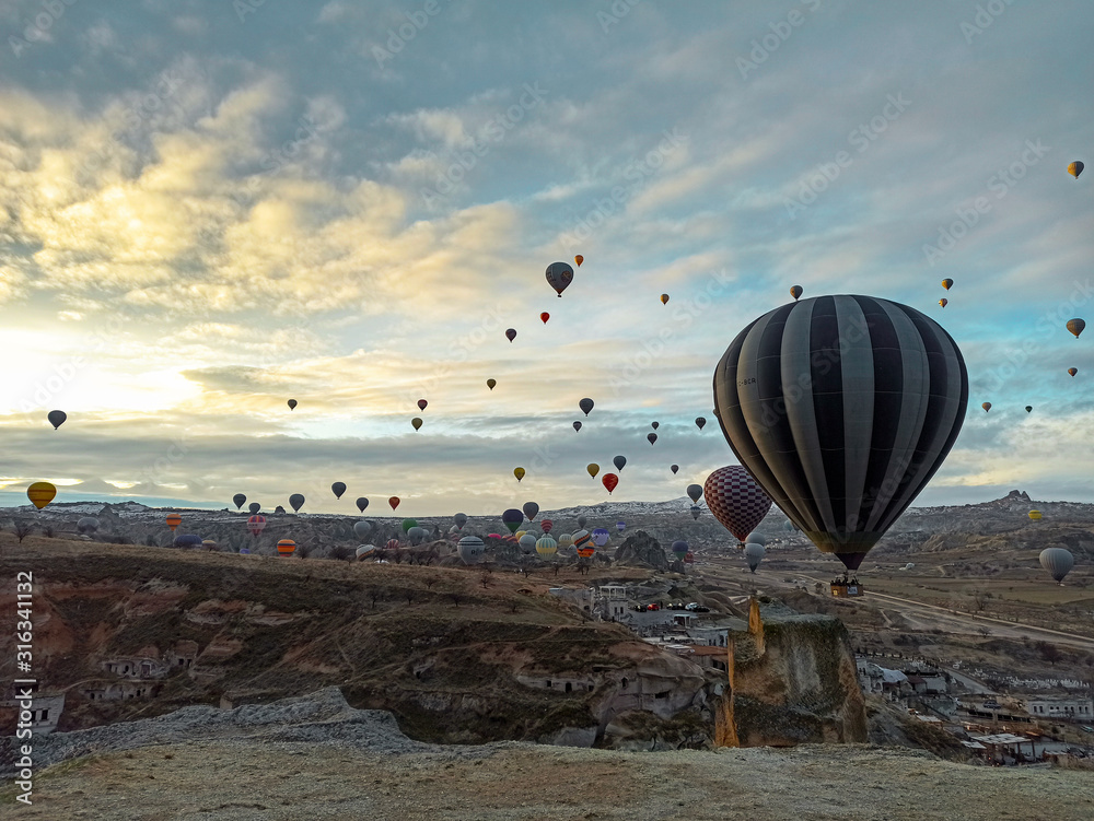 Colorful hot air balloons flying at the sunrise  with rocky landscape in Cappadocia, Turkey