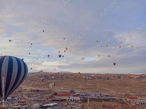 Colorful hot air balloons flying at the sunrise with rocky landscape in Cappadocia, Turkey
