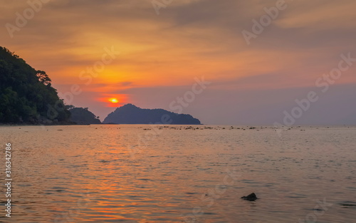view of mountain in the sea with orange sun light in the sky background  sunset at Khao Chong Kad  Surin island  Mu Ko Surin National Park  Phang Nga  southern of Thailand.