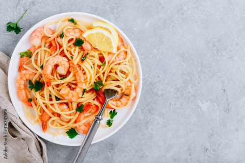 Seafood Pasta spaghetti with shrimps and parsley on gray stone background.