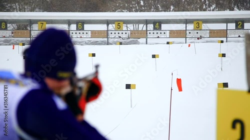 A skier shoots a rifle at a target. Skier takes part in the biathlon race, standing aimed at the target and made a shot. photo