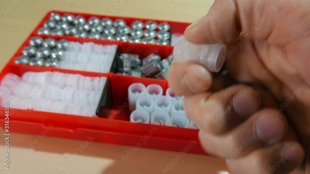 A box with components of hunting cartridges is on the table. A man chooses a 20-caliber bullet to equip a cartridge. A box with components of hunting cartridges is on the table. A man chooses a 20-caliber bullet to equip a cartridge.