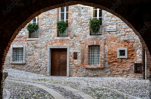 Fototapeta Naklejka Na Ścianę i Meble -  Medieval street arch under an ancient brick wall of a building facade in the town of Cividale del Friuli. Udine, Friuli Venezia Giulia, Italy