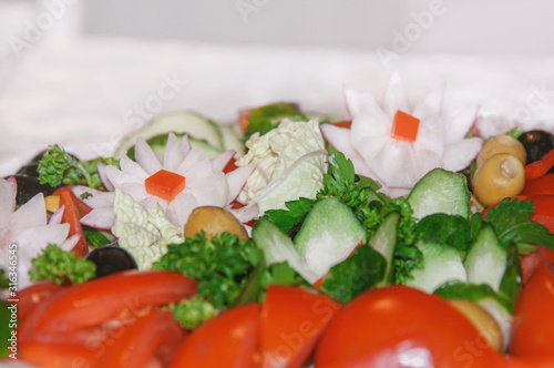 Vegetable salad with juicy tomatoes, radishes, lettuce, green olives, cucumber, red onion and fresh parsley. Homemade food. The concept of delicious and healthy vegetarian food. Close up