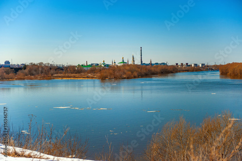 Spring natural landscape of spring flood. Ice floes float on the river in the ice drift. Sunny day with blue clear sky