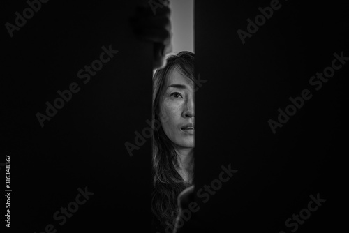 woman showing afraid emotional with gesture when she opening the closet att night in white tone.