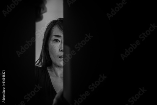 woman showing afraid emotional with gesture when she opening the closet att night in white tone.