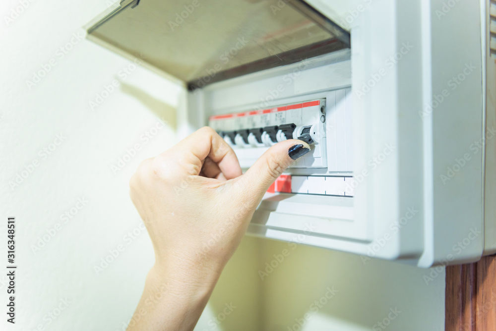 Circuit breaker board displays many switches. A finger of woman is turning it back on. Circuit breaker board displays many switches. A finger of woman is turning it back on.