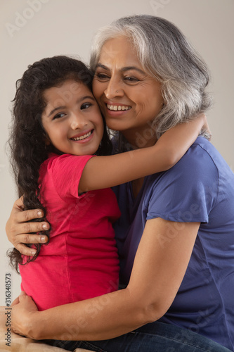 Portrait of a happy grandmother hugging her grand-daughter.  	