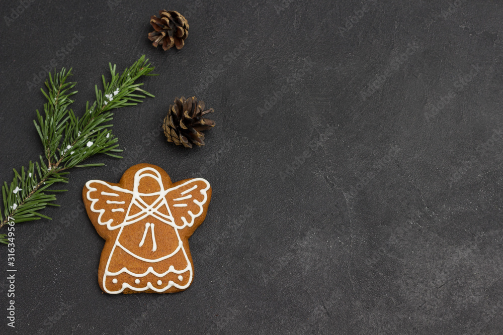 Fototapeta premium Christmas gingerbread cookie in shape of angel, green topping on black background, holiday cookies.